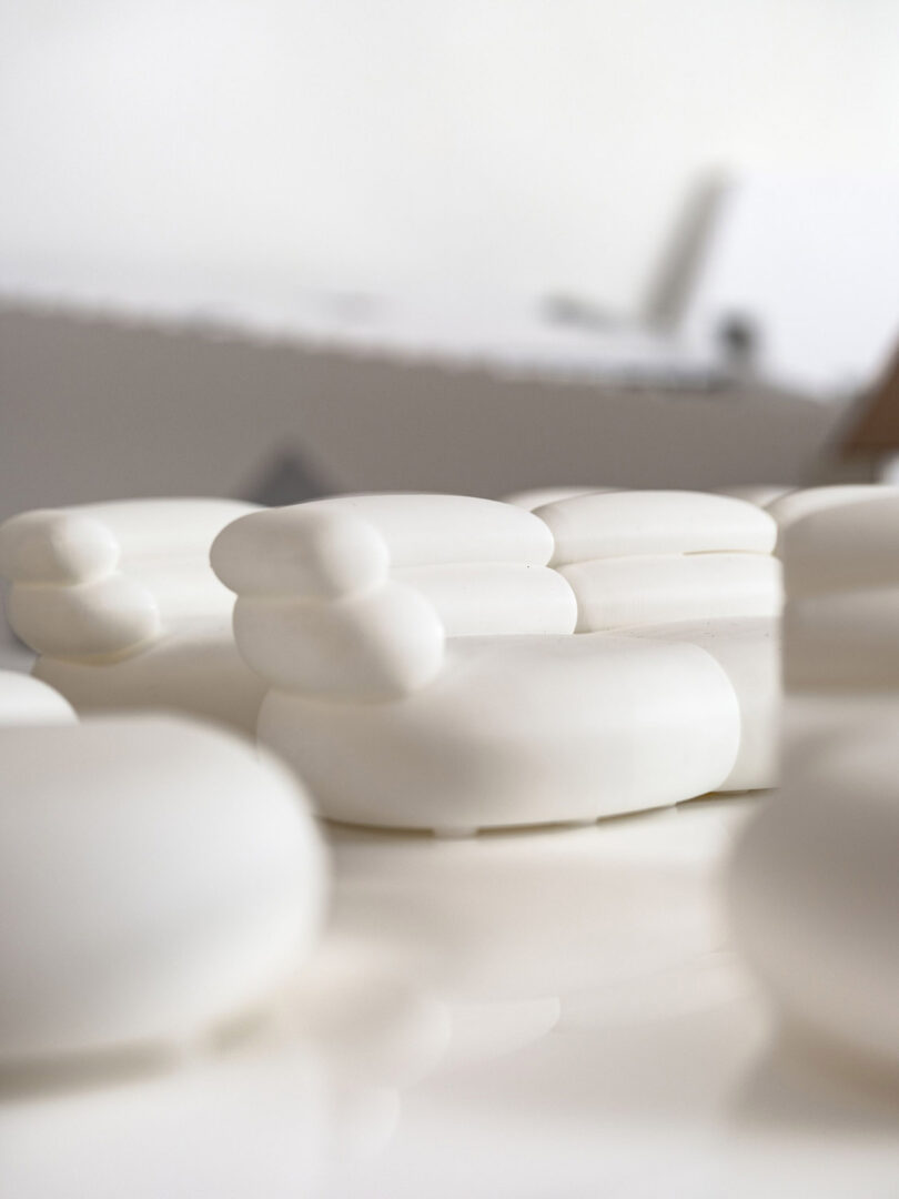 Formas ovaladas y redondas de color blanco brillante dispuestas sobre una superficie lisa con fondo blanco borroso.