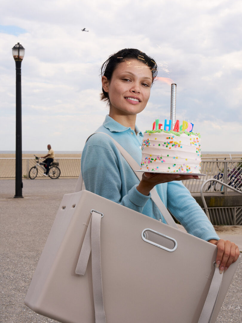 Al aire libre había un hombre que sostenía en una mano una tarta de cumpleaños con velas y azúcar glas de colores y una gran bolsa rectangular al hombro.