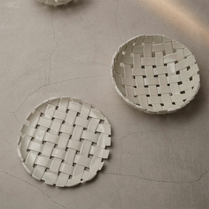 Dos cestas redondas de cerámica blanca con un patrón tejido descansan sobre una superficie de textura ligera, perfectas como regalo elegante para el chef.