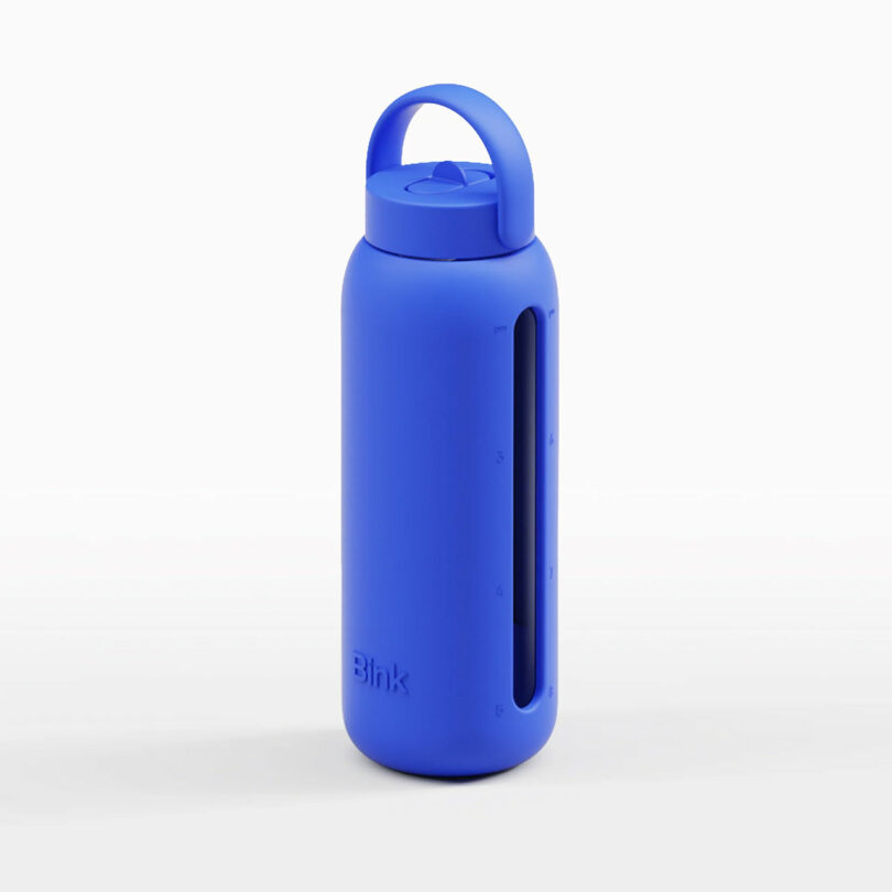 A blue reusable water bottle with a handle on the lid and a transparent vertical strip showing measurement markings on the side.