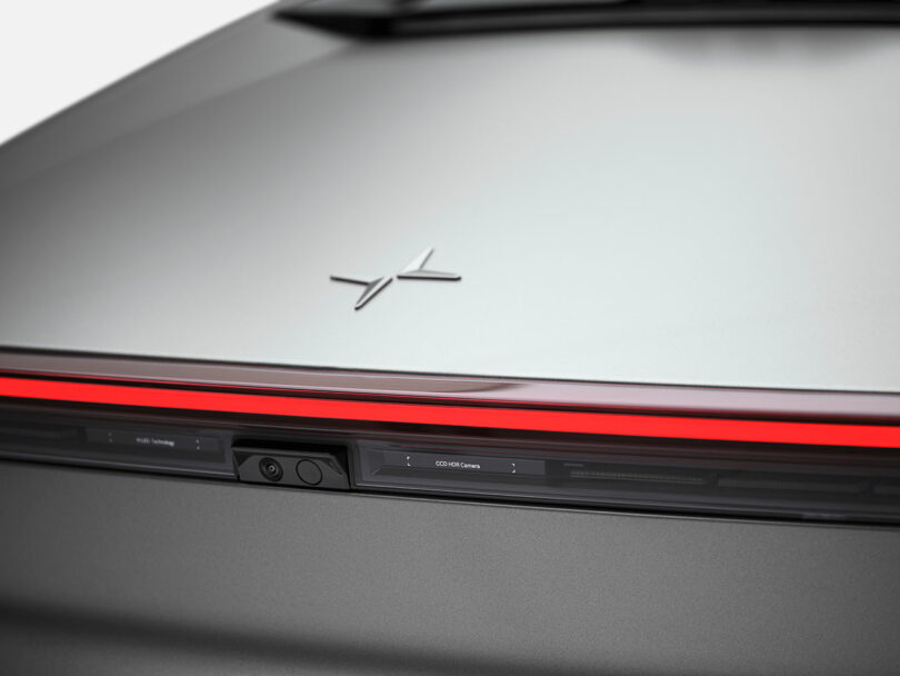 Un primer plano de la parte trasera de un automóvil plateado, que muestra el logotipo de Polestar y la barra de luces traseras LED rojas.