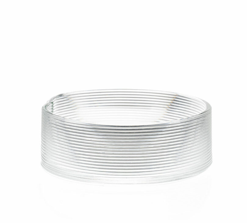 A clear glass bowl with horizontal ribbed lines sits on a white background.
