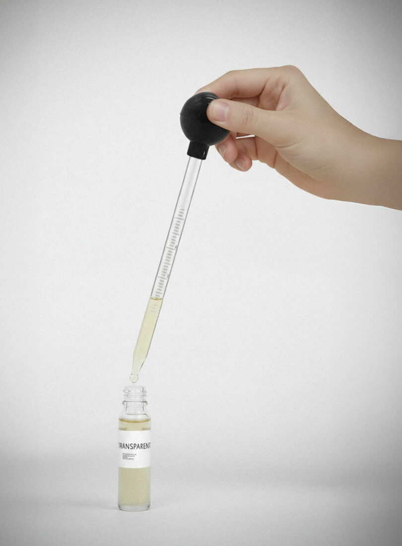 A hand holds a dropper above a small glass bottle labeled "TRANSPARENT," with liquid being dispensed—perfect for use in an aroma diffuser.