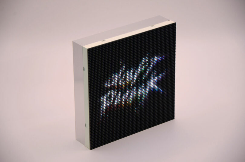 El panel de visualización LED rectangular muestra coloridos gráficos pixelados y texto ilegible sobre un fondo sólido.