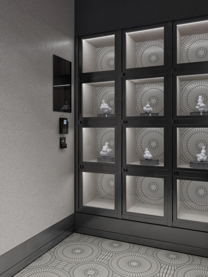 Una fila de vitrinas de color negro brillante, cada una con una escultura abstracta blanca, contra un piso y una pared estampados, con un panel de control instalado cerca