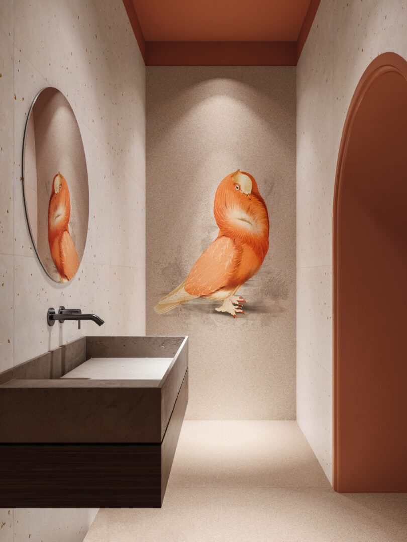 Cuarto de baño moderno con espejo redondo, lavabo rectangular y un gran pájaro naranja colgado en la pared frente al lavabo.