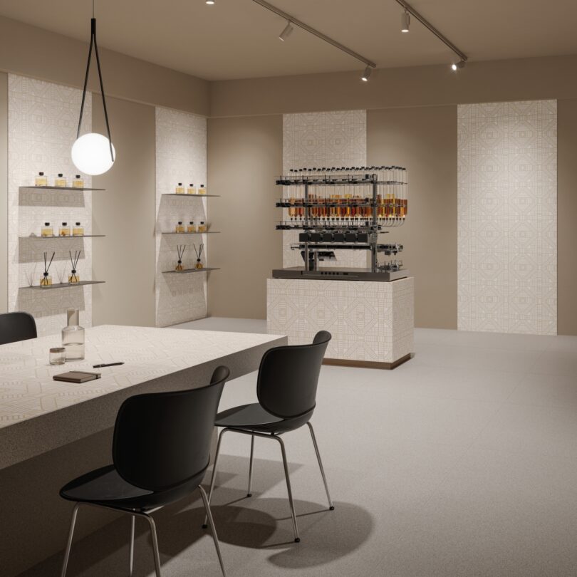 Interior moderno y minimalista de perfumería con estantes, mostrador central con frascos de perfume y dos sillas negras sobre la mesa bajo la lámpara de araña