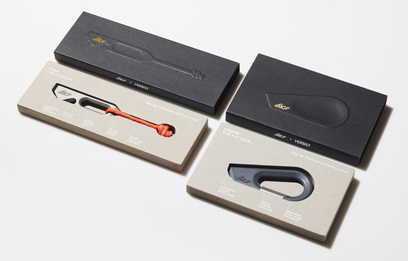 Dos cuchillos utilitarios en caja, uno naranja y otro negro, presentados en un empaque sencillo con una ventana transparente e información del producto impresa en el frente.