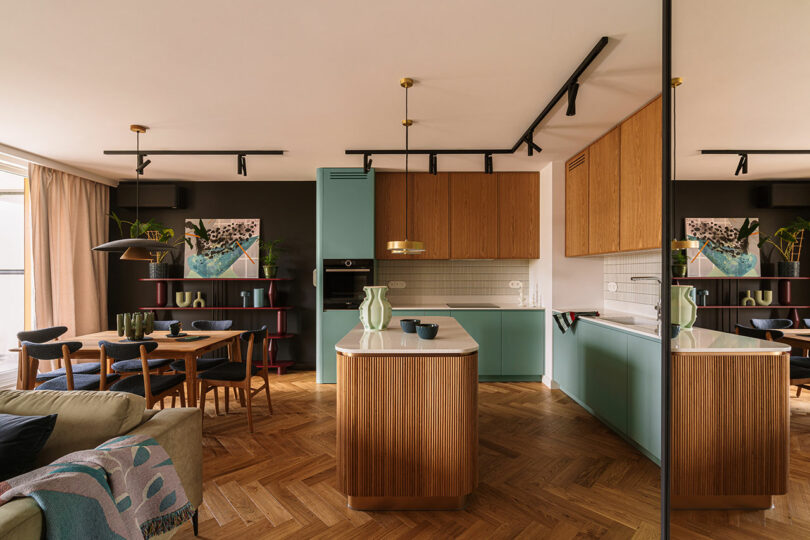 Moderna cocina y comedor de planta abierta con gabinetes de madera y verde menta, isla central, pisos de parquet y decoración moderna