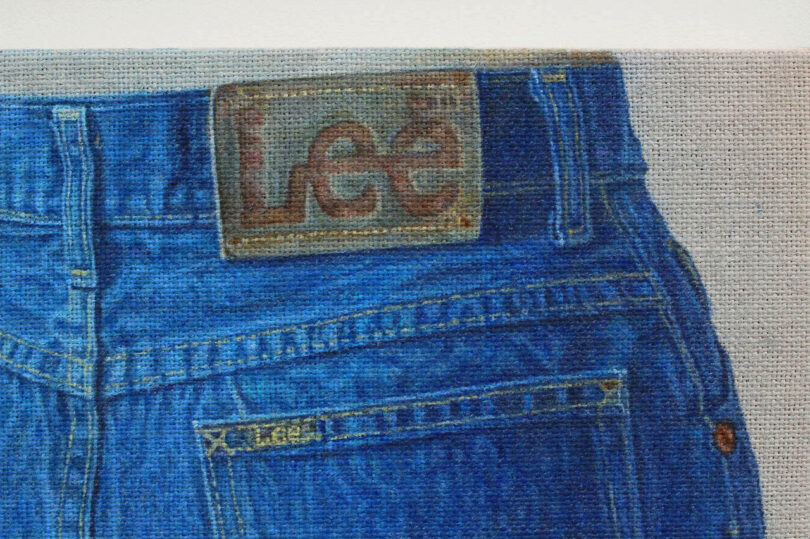 Primer plano de la parte trasera de unos jeans Lee azules, que muestra la etiqueta de la marca cosida en la cintura y la pequeña etiqueta Lee encima del bolsillo.