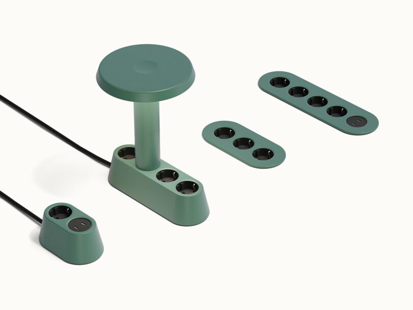 Sistema modular de regleta verde con múltiples enchufes y unidades extraíbles dispuestas sobre una superficie blanca.