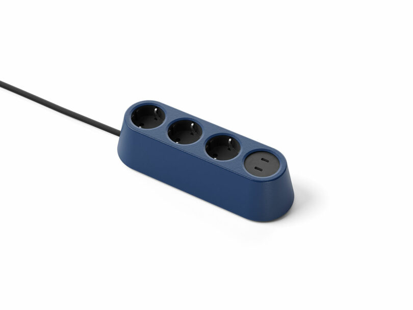 Regleta azul con tres enchufes europeos redondos y un enchufe negro redondo sobre fondo blanco, conectado a un cable de alimentación negro.