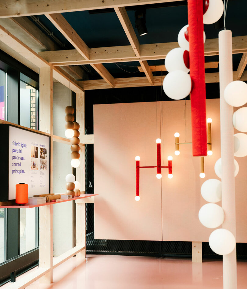 Los interiores modernos con marcos de madera, textiles Byborre, lámparas esféricas y cilíndricas, paneles informativos y diversos objetos decorativos crean un ambiente luminoso y minimalista.