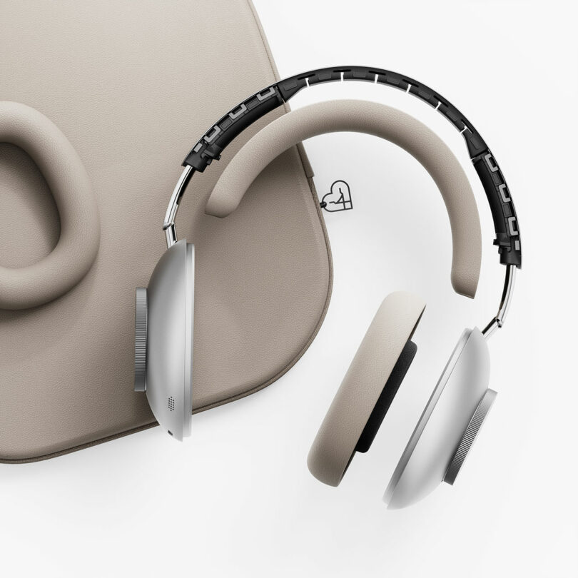 Los auriculares supraaurales beige y plateados se asientan sobre superficies acolchadas a juego, ambos con diseños minimalistas y texturas suaves sobre un fondo blanco.