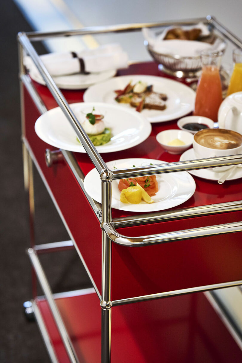 Un camión de comida rojo contiene diversas delicias, una taza de café, una taza de jugo, cubiertos y servilletas.