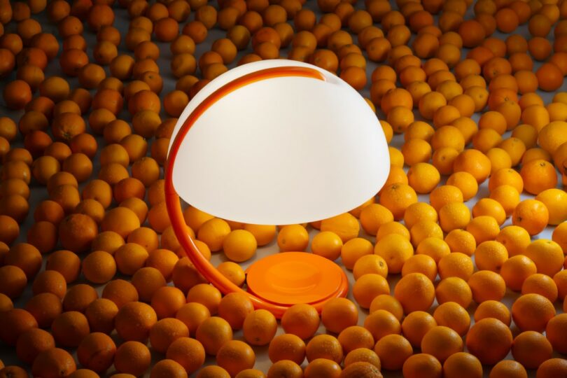 Una moderna lámpara de mesa naranja y blanca se coloca entre los muchos naranjas que cubren la superficie.