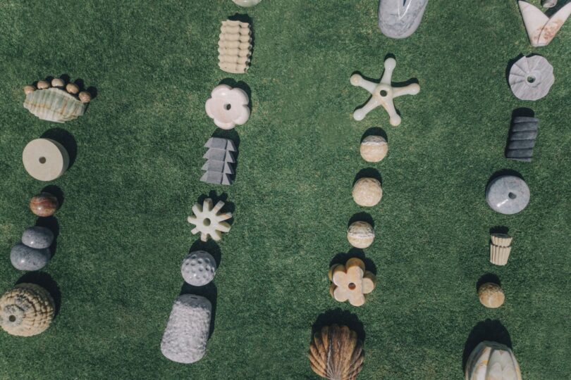 Herramientas de piedra de diversas formas y colores dispuestas verticalmente sobre la hierba verde