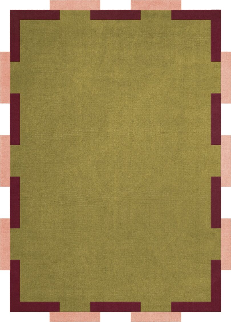 Una alfombra rectangular con un centro verde oliva rodeado por una banda roja y piezas rectangulares de color rosa claro que se extienden a lo largo de los bordes.