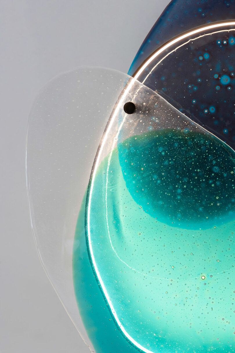 Cierre la transparencia de vidrio azul en la pared blanca.