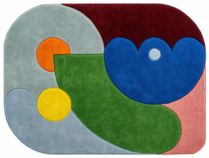 Alfombra rectangular redondeada con formas abstractas en verde, azul, rojo, gris, amarillo y naranja en un diseño geométrico moderno inspirado en Sam Buckley.