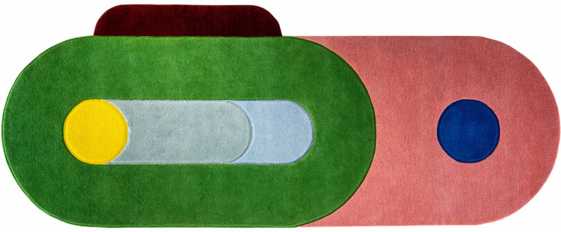 La colorida alfombra geométrica de Sam Buckley presenta formas superpuestas en tonos de verde, rosa, rojo, amarillo, azul y gris dispuestas en llamativos patrones abstractos.