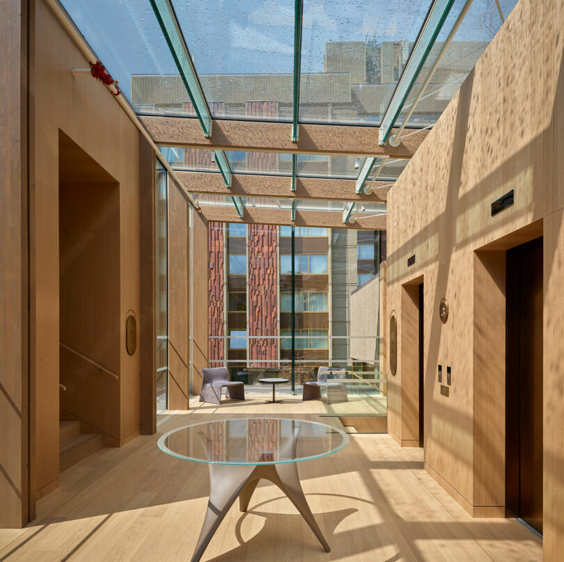 El interior moderno cuenta con paneles de madera, mesas redondas de cristal, dos ascensores y techos de cristal que inundan el espacio con luz natural y dan a un edificio con una fachada estampada.