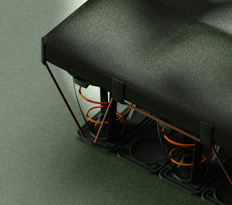 Primer plano de un colchón moderno que muestra resortes expuestos, una capa superior de tela y una base de rejilla de plástico sobre un piso de color sólido.