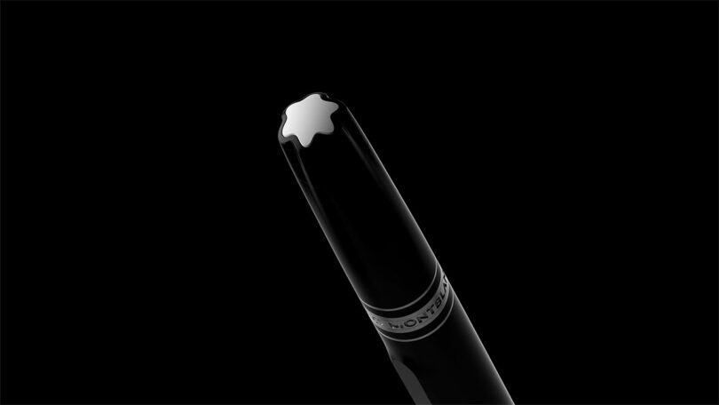 Close-up of the top of a black pen with a white star-shaped emblem and a metallic ring, photographed against a black background in sleek Fuseproject style.