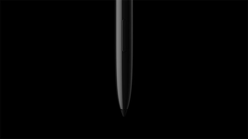 A black stylus pen, designed by Fuseproject, is centered vertically against a solid black background, with the tip pointing downward.