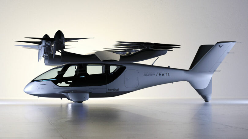 Un moderno avión eléctrico de despegue y aterrizaje vertical (eVTOL) con cuatro rotores se muestra en tierra en un ambiente interior bien iluminado.