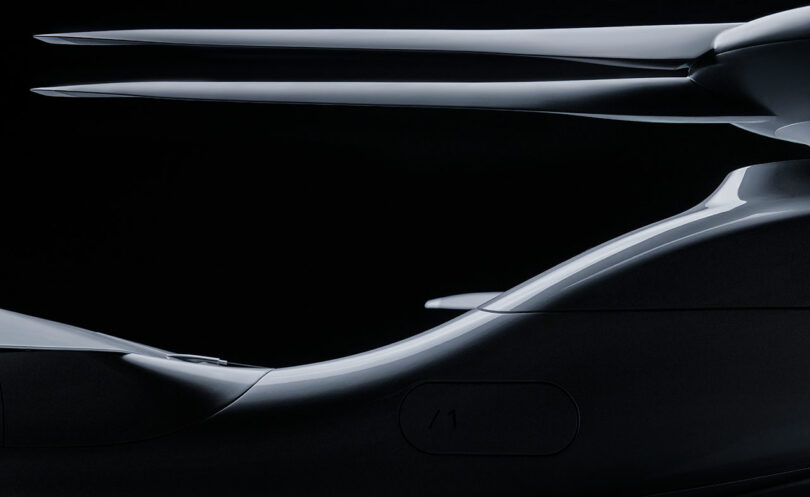 Vista lateral de primer plano de un diseño elegante y futurista de vehículos o aviones con curvas suaves y una estructura alargada en forma de cuchilla sobre un fondo oscuro.