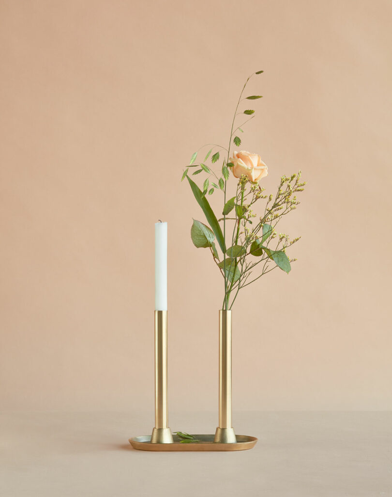 A candle and a rose in a brass vase.