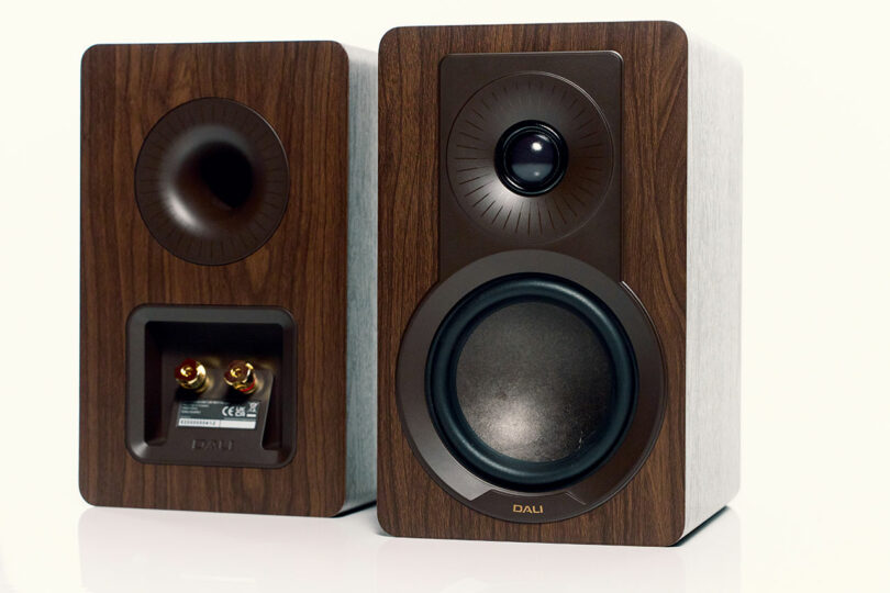 Two modern DALI wooden bookshelf speakers, one showing the front with a woofer and tweeter, the other displaying the back with connection ports.