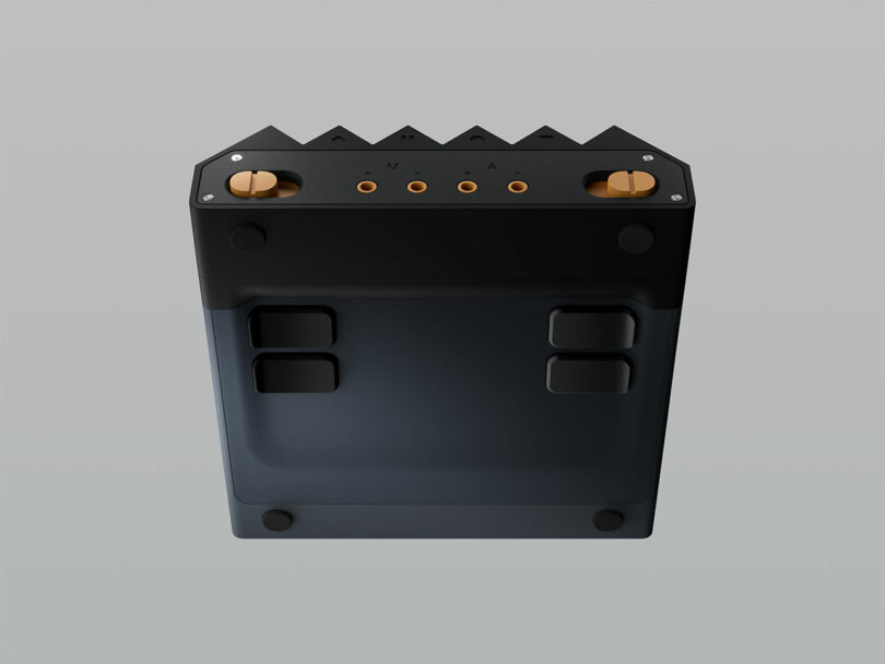 A rectangular electronic device with four round knobs, five ports, and labeled controls on top, viewed from a slightly elevated angle against a gray background.