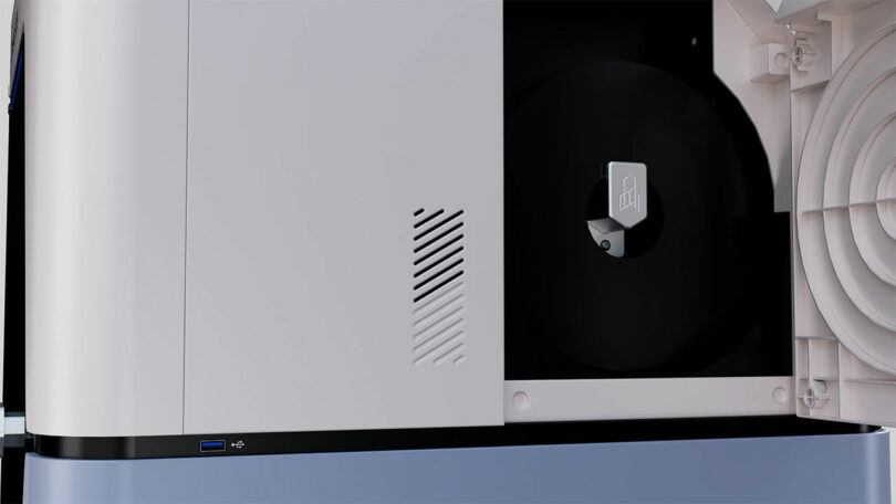 Primer plano de una impresora o fotocopiadora moderna con panel abierto que muestra los componentes internos, puertos USB en el exterior y conexión FibreSeeker para mejorar la transferencia de datos.