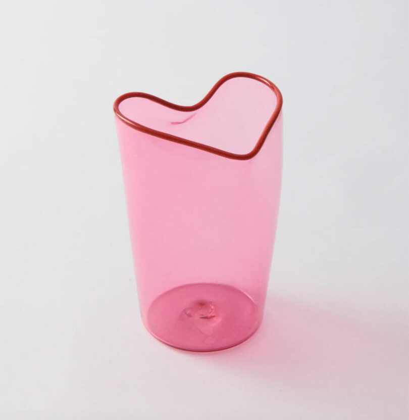 A translucent pink glass cup with a heart-shaped rim, perfect for Valentine's Day Gifts, placed on a plain white surface.