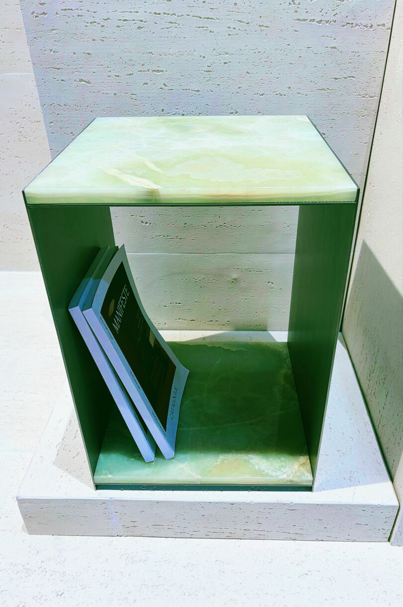 A rectangular green marble shelf holds three angled books on its lower level, inviting you to Take 5 against a light-colored stone wall and floor.