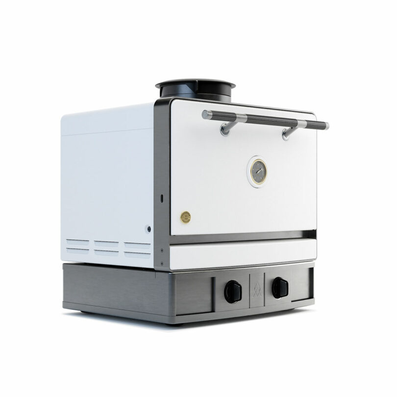 The Emberhaus is a compact, modern countertop oven with a white front, stainless steel handles, a temperature gauge, and control knobs at the base.