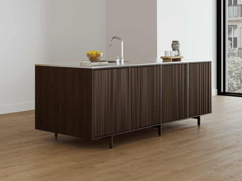 La moderna isla de cocina Vipp presenta un acabado en madera oscura, encimeras de mármol, un fregadero con grifo y elementos como un cuenco de limones y frascos de vidrio.