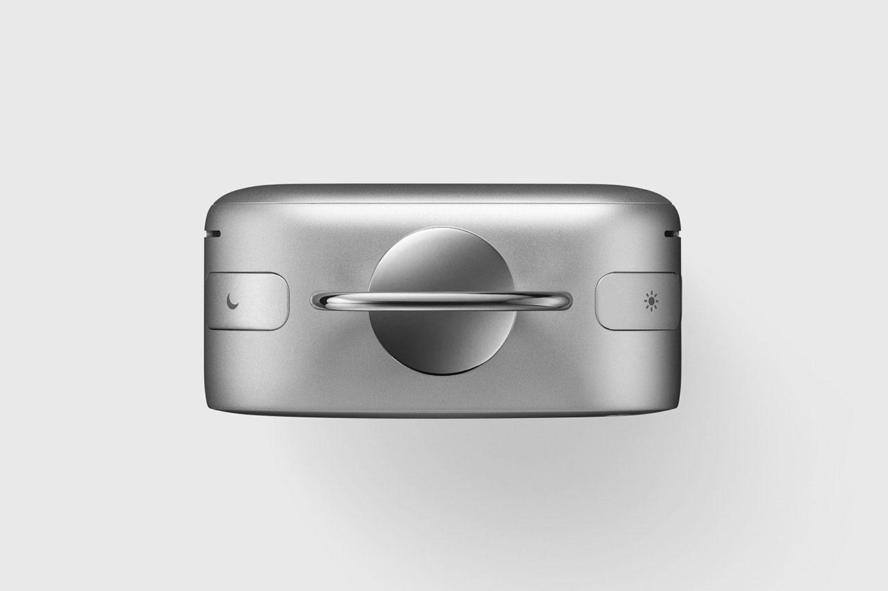 A silver rectangular device with a central rotating knob, featuring a moon icon on the left button and a sun icon on the right button, against a plain light background.