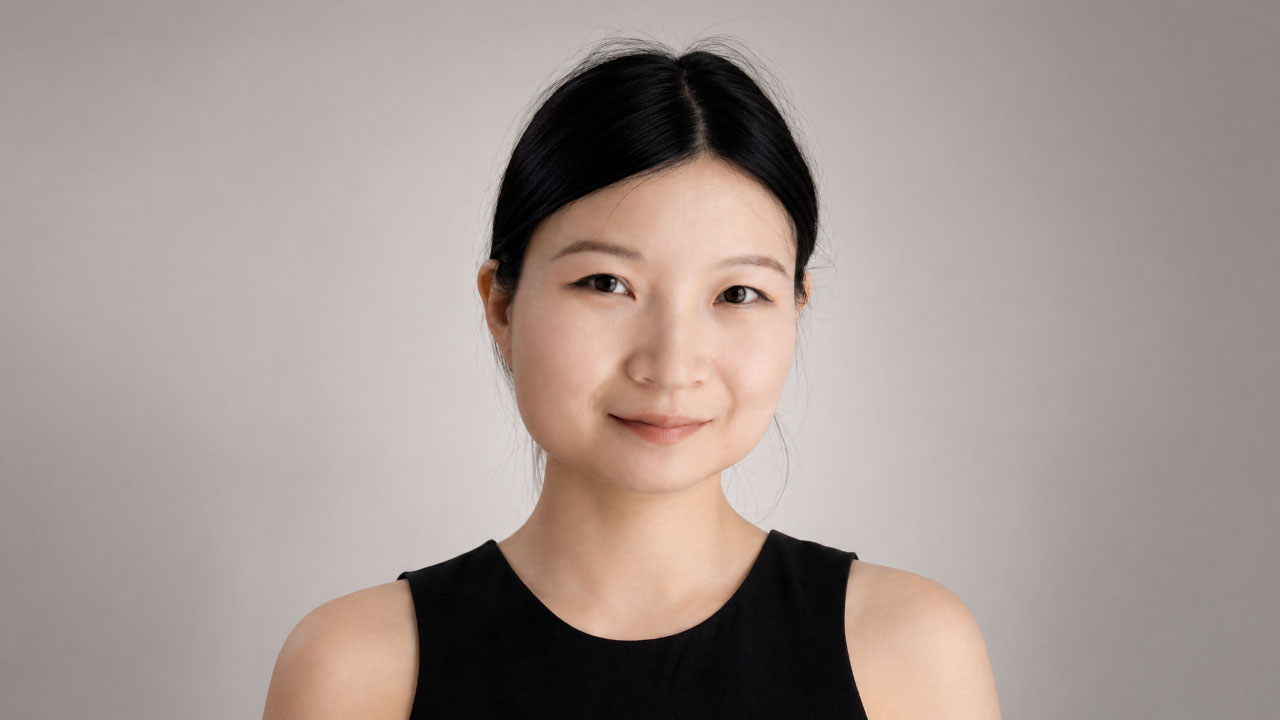 A woman with straight black hair, wearing a sleeveless black top, poses against a plain light gray background for this Friday Five feature.