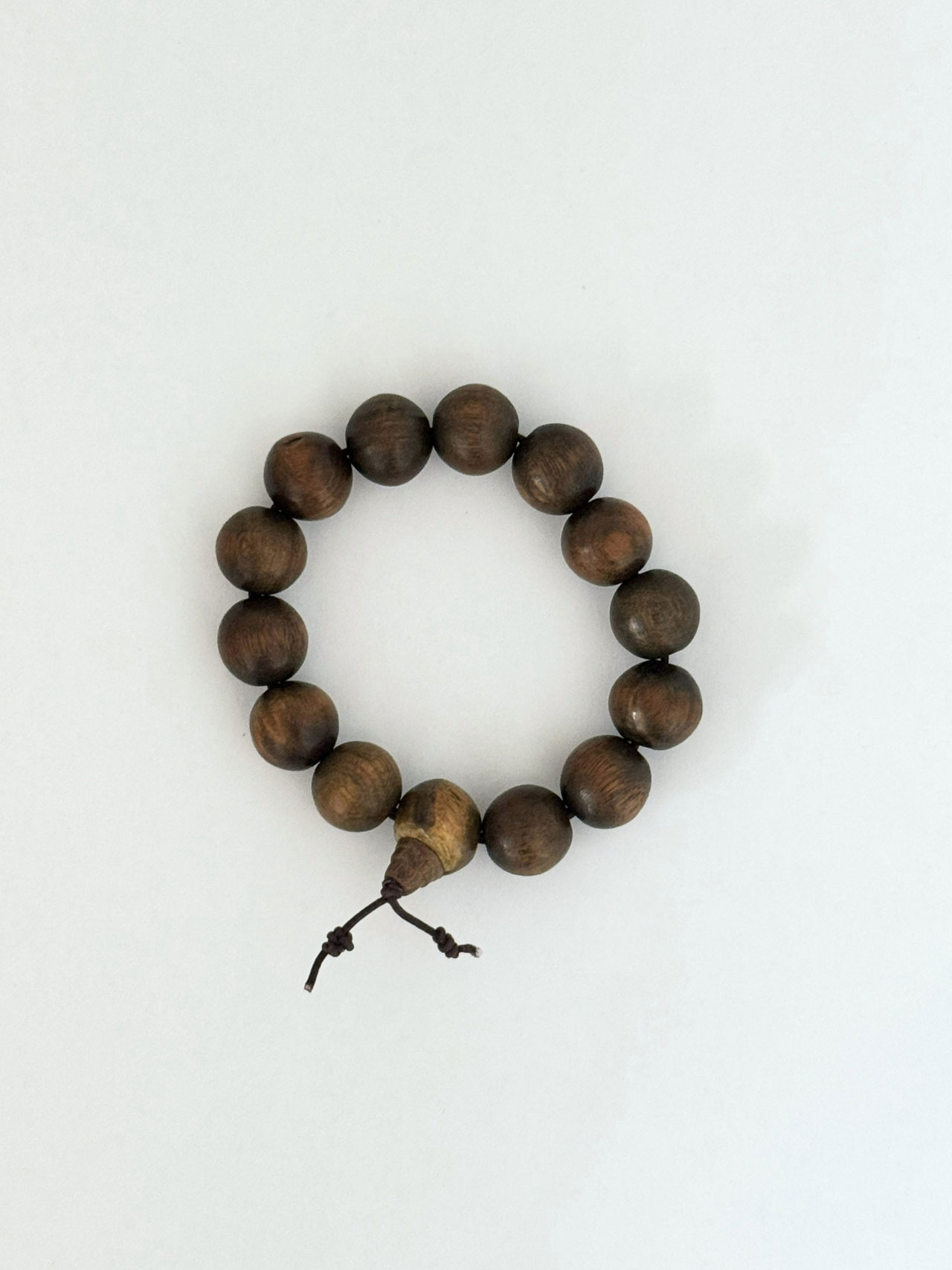 A wooden bead bracelet with fourteen round beads and a knotted string, arranged in a circle on a plain white background—perfect for your Friday Five essentials.