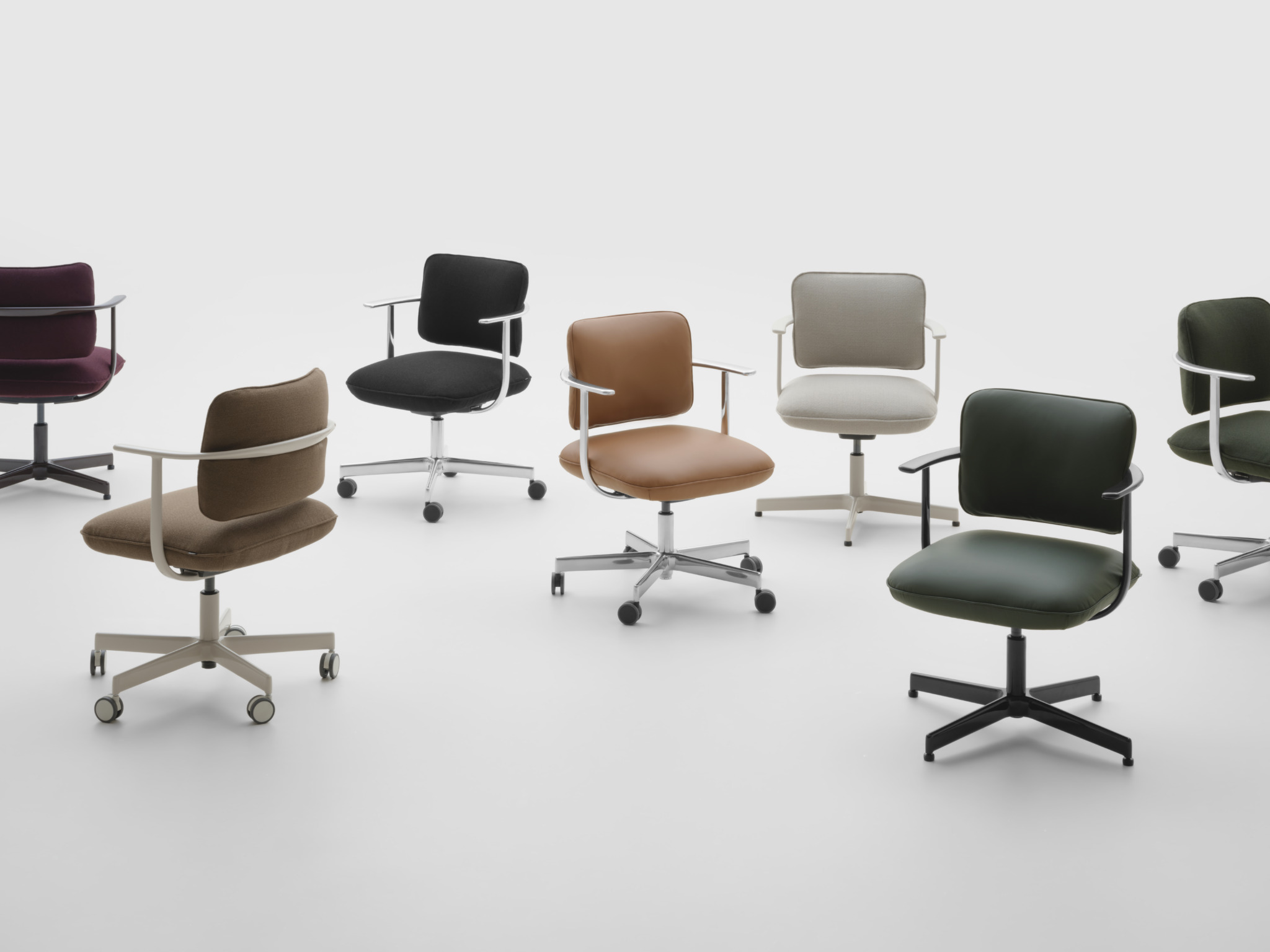 Seven modern office chairs in different colors and materials are arranged on a plain white background.
