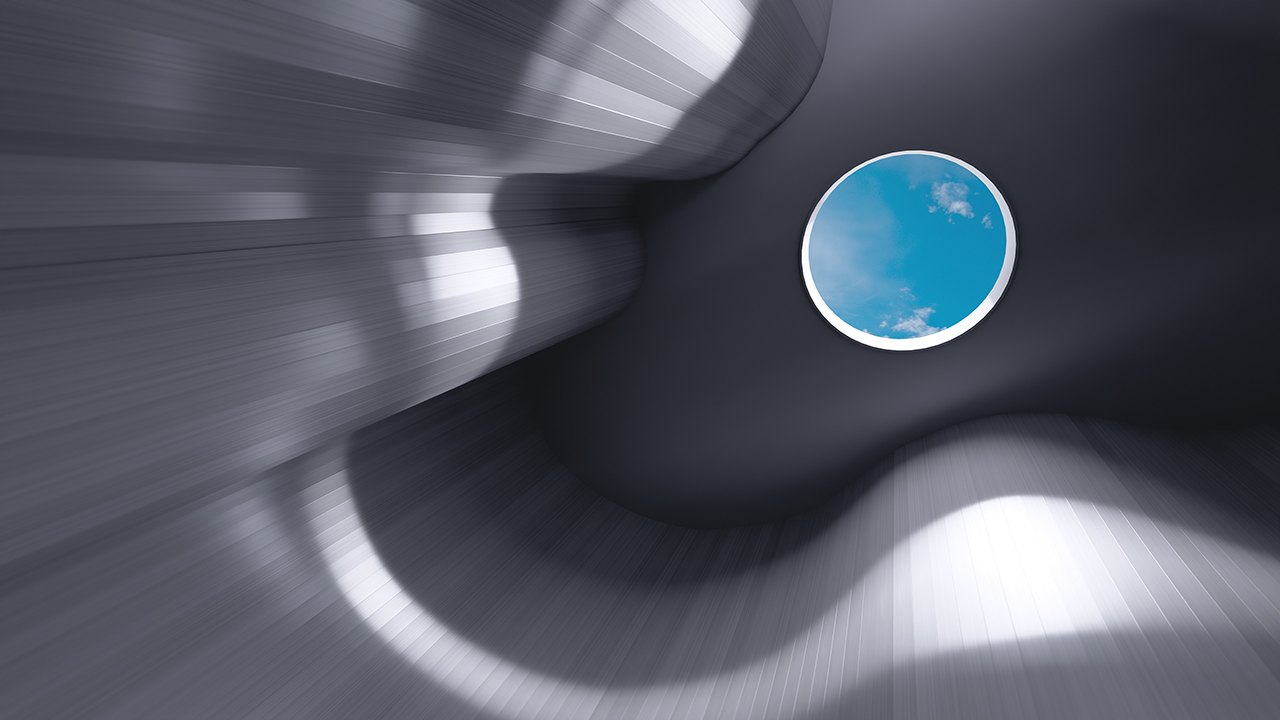 Abstract view of a curved metallic structure with a round skylight showing blue sky and clouds.