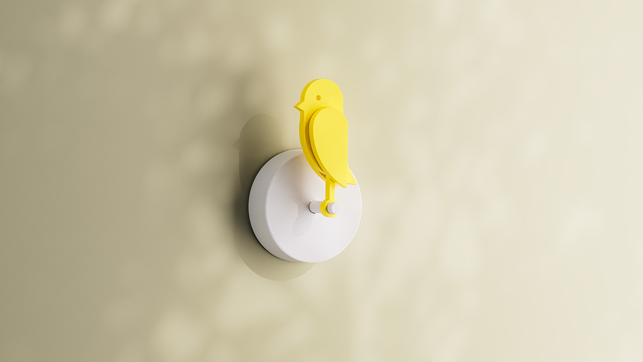 Un objeto amarillo con forma de pájaro está montado sobre una base blanca redonda que está anclada a una pared de color claro.