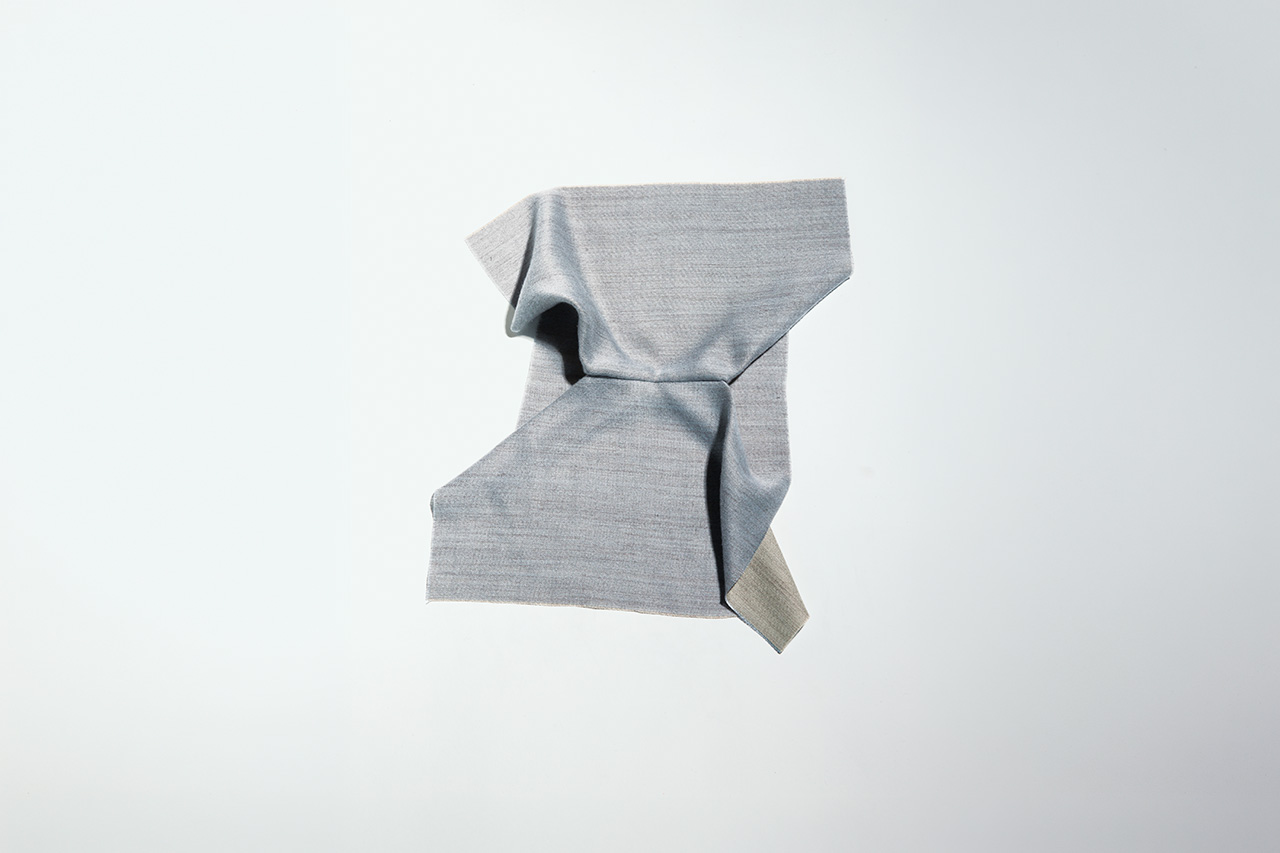 A piece of light gray fabric with a textured surface is loosely folded against a plain, light background.