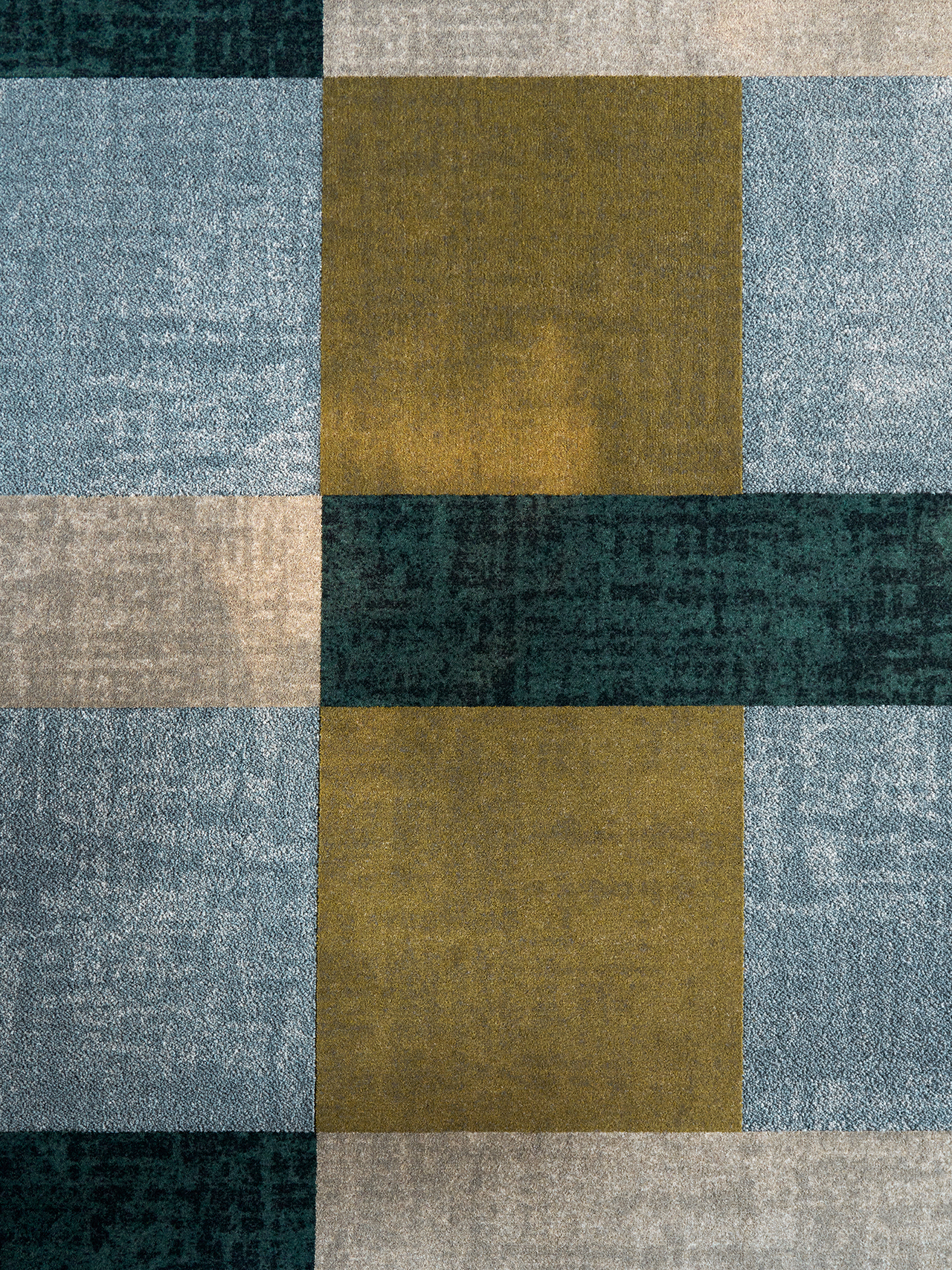 A geometric pattern featuring large rectangles in muted shades of blue, green, beige, and gold arranged in a grid layout.