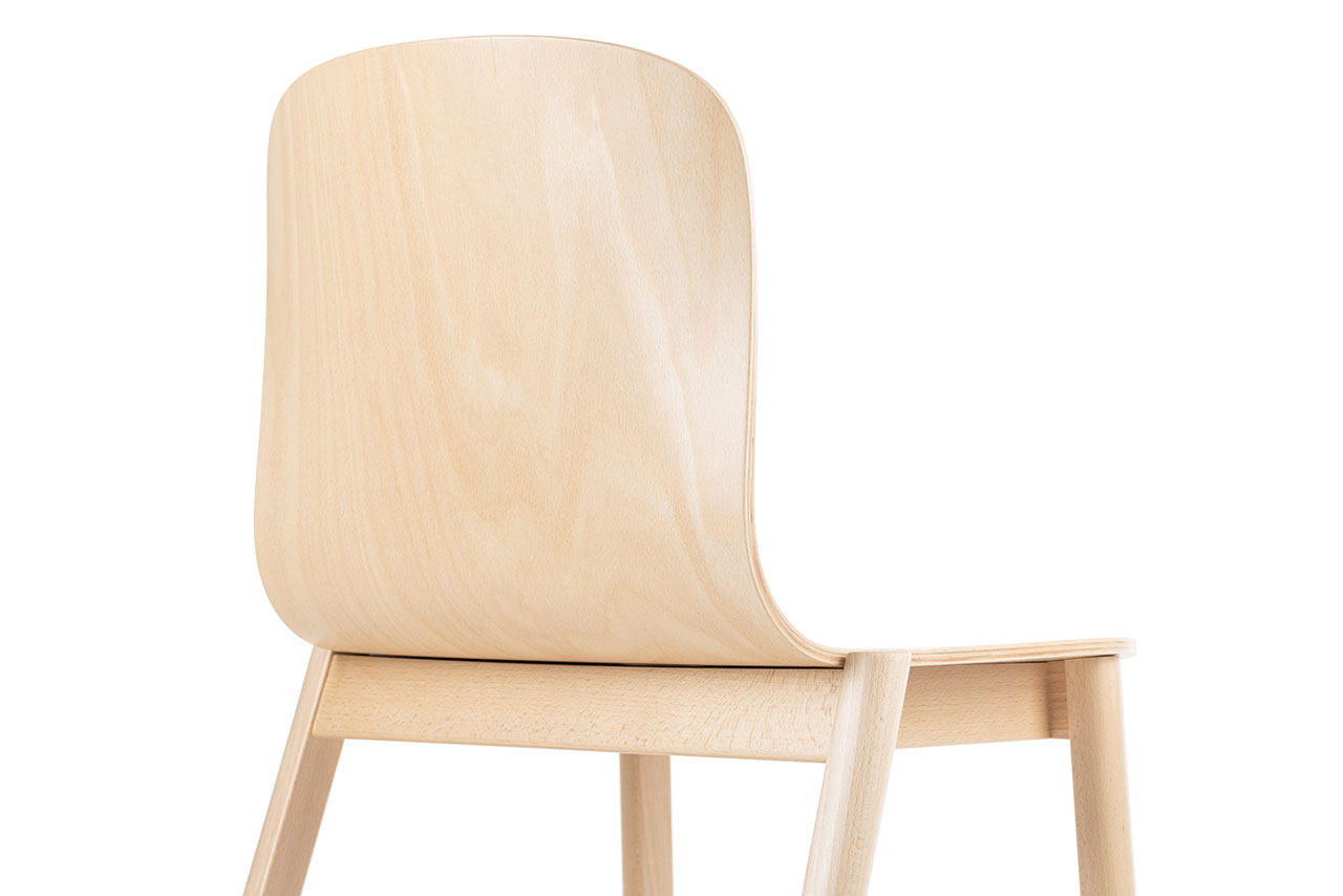 Esta silla de madera clara de Alexander Gufler está fotografiada desde atrás, mostrando su respaldo suave y curvado y su diseño minimalista.