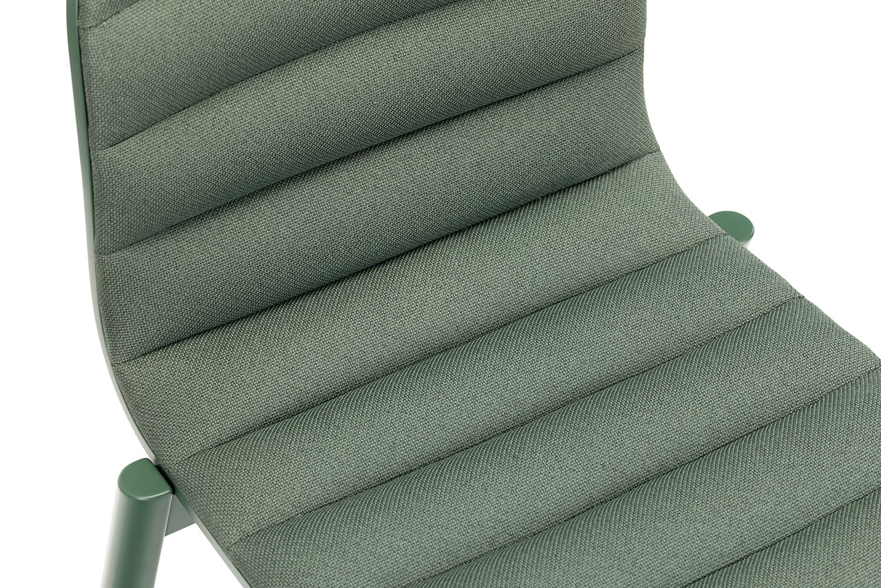 Primer plano de una silla moderna de Alexander Gufler con textura verde, tapizado acanalado y estructura de metal, vista desde un ángulo superior.