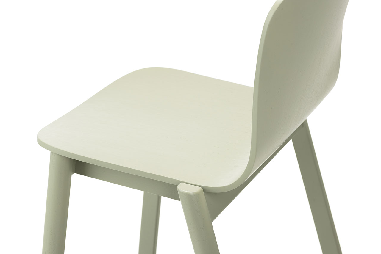 Silla de madera clara de Alexander Gufler con asiento y respaldo curvos en vista lateral inclinada sobre fondo blanco.